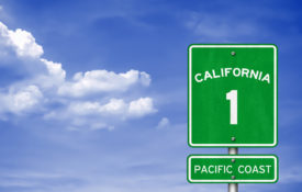 Green Highway 1 Pacific Coast sign in front of a blue sky