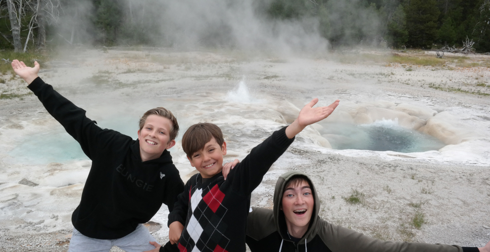 Three boys ham it up in front of a thermal feature at Yellowstone National Park