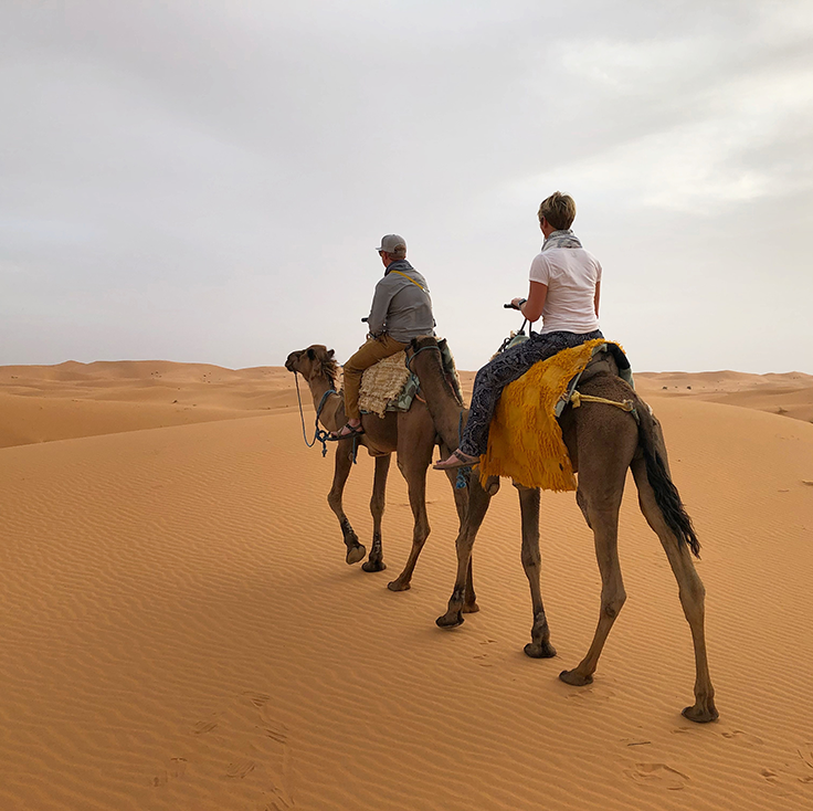Kelly Palmer and her husband ride camels through the desert in Morocco