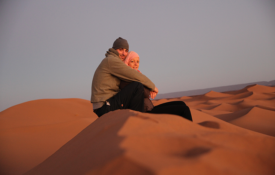 OBP Travel Designer Julianne Mohr and her husband sit on the sand dunes of Morocco