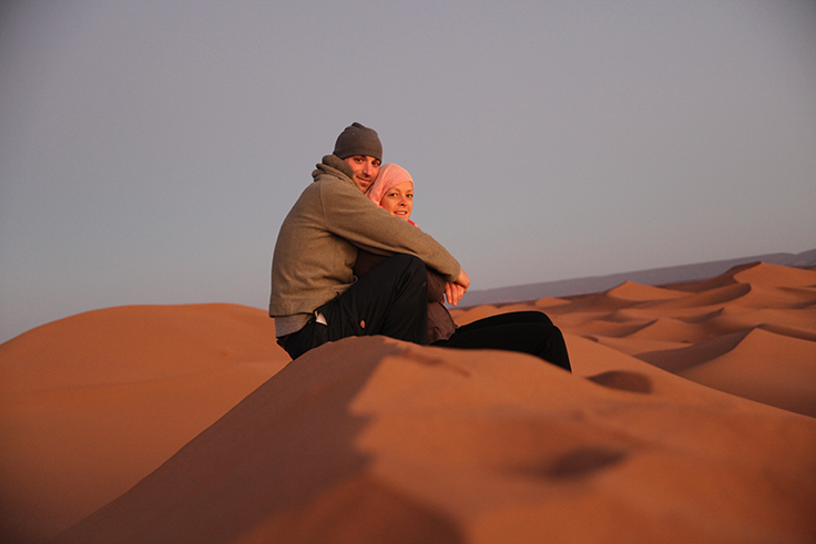 OBP Travel Designer Julianne Mohr and her husband sit on the sand dunes of Morocco