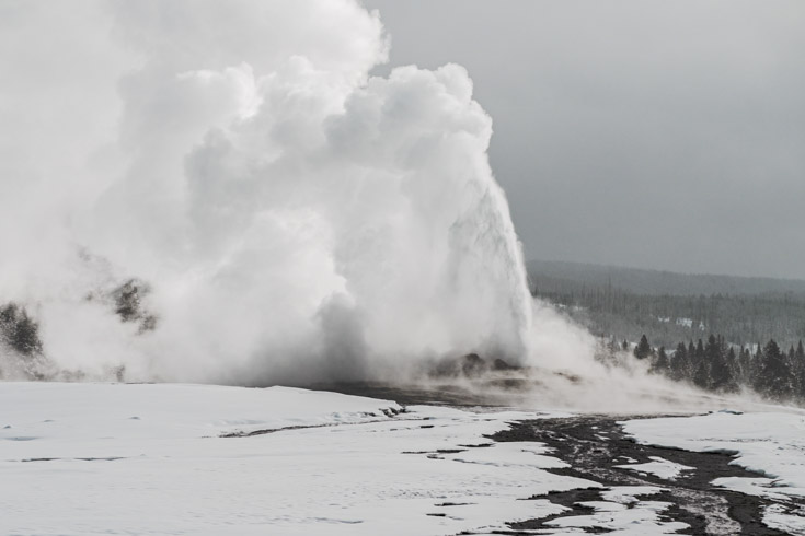Old Faithful billows clouds of steam into the winter sky.