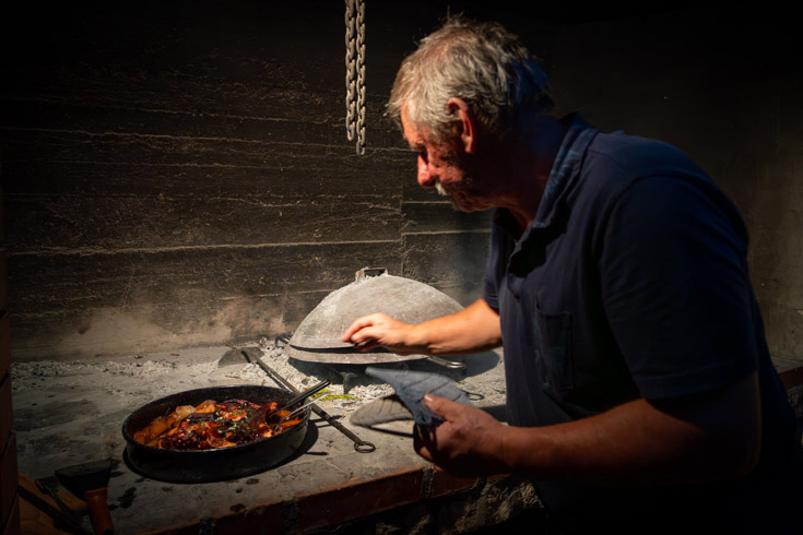 A man prepares a traditional "under the bell" peka meal 