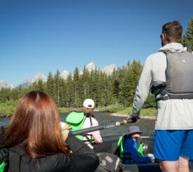 river guide on the snake river with the teton mountains in the background