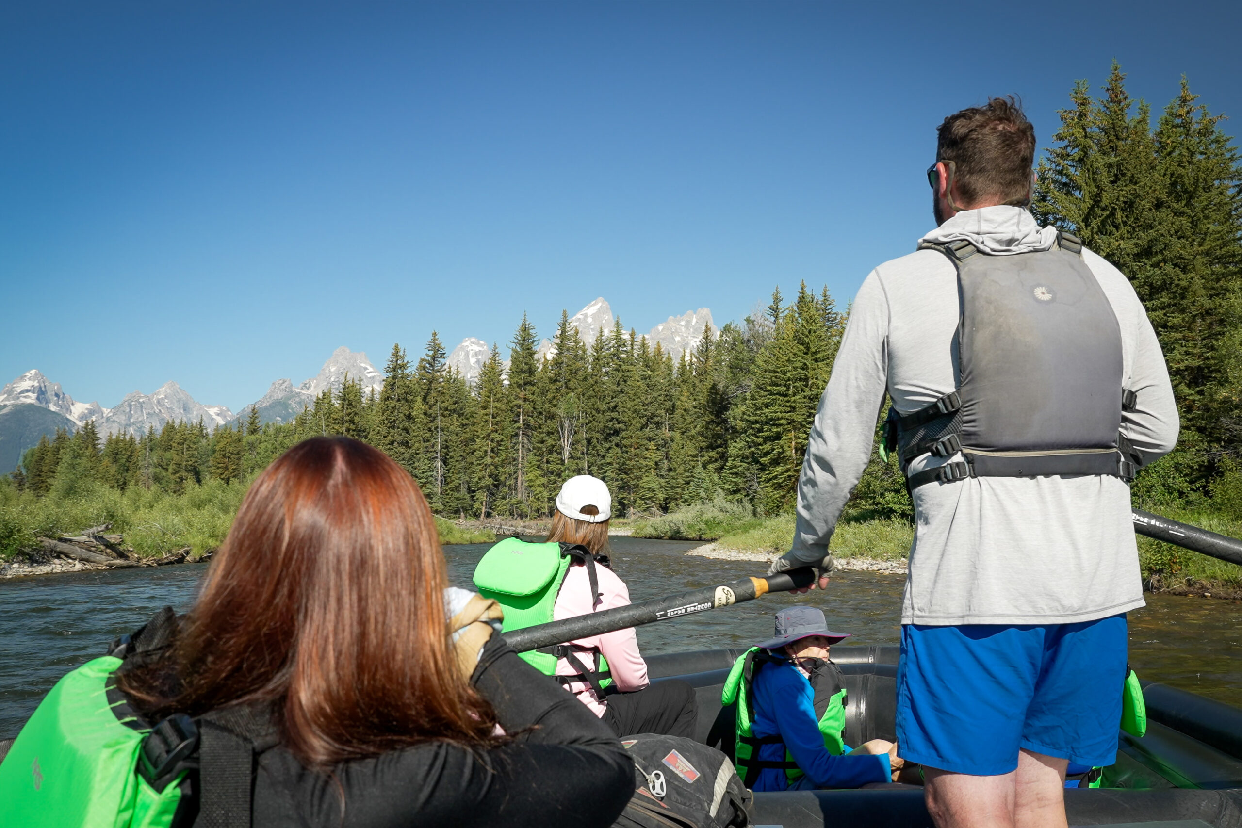river guide on the snake river with the teton mountains in the background